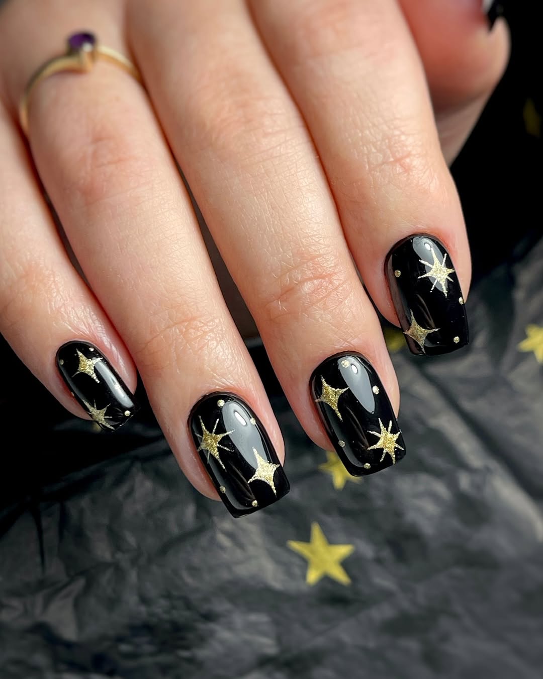 Glimmering Gold Stars on Glossy Black Nails