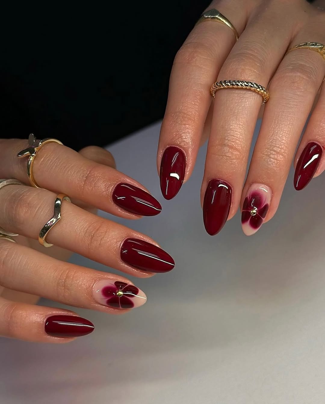 Glossy Deep Burgundy Almond Nails with Floral Accent