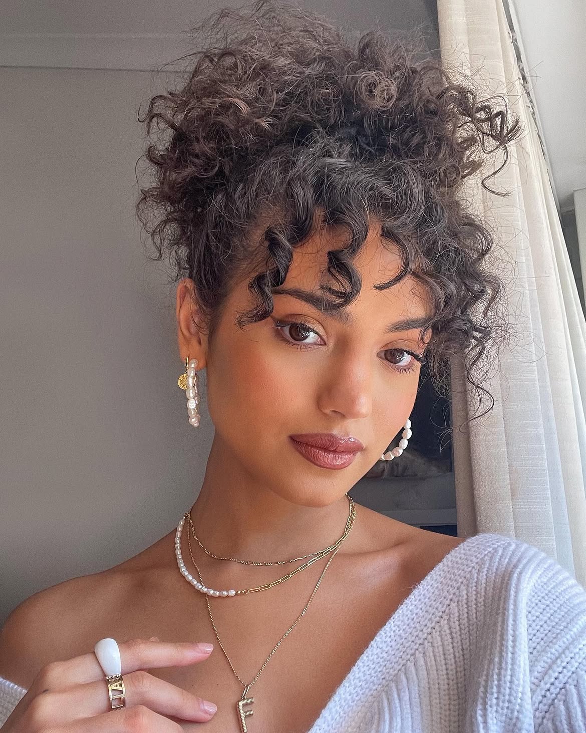 Effortless Curly High Bun With Face-Framing Tendrils