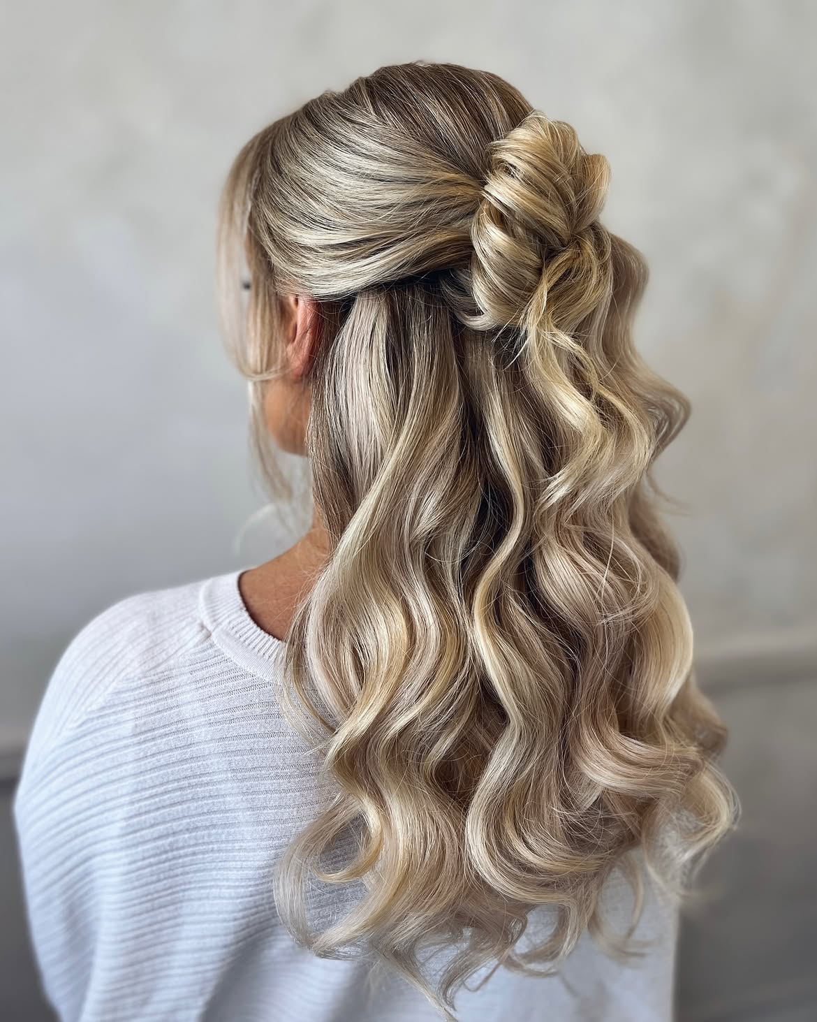 Elegant Wavy Half Updo With Chic Knotted Detail