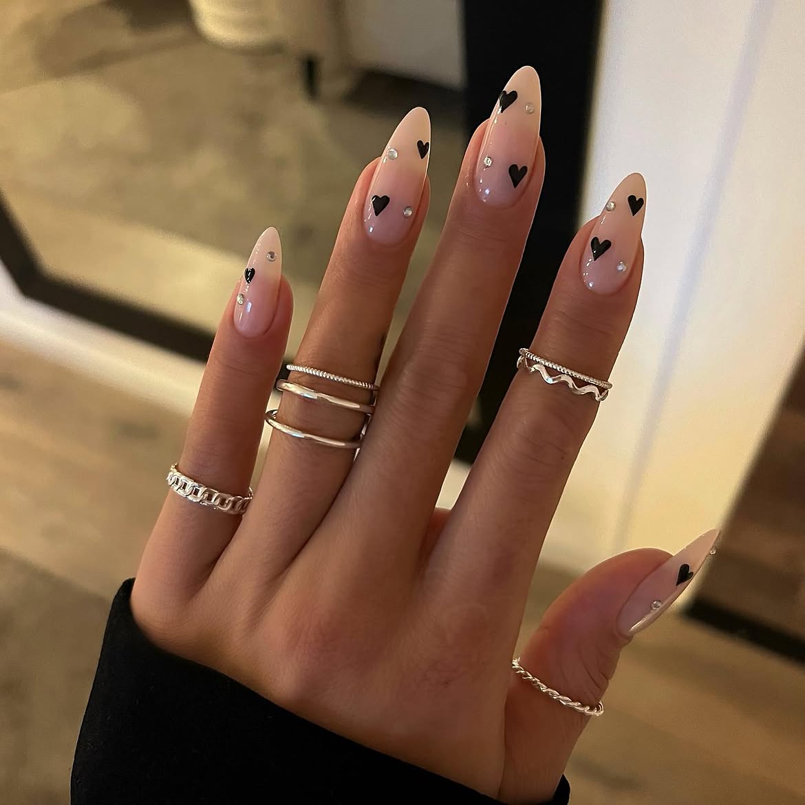 Glossy Nude Almond Nails With Black Hearts And Rhinestones