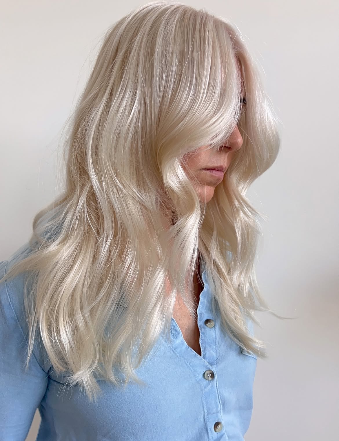 Voluminous Platinum Blonde Layers With Face Framing Curtain Bangs