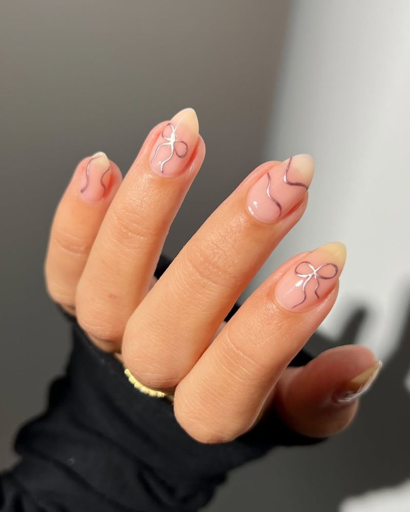 Sheer Nude Medium Almond Nails With Silver Bow Lines Sheer Nude Medium Almond Nails With Silver Bow Lines — Bow Nails