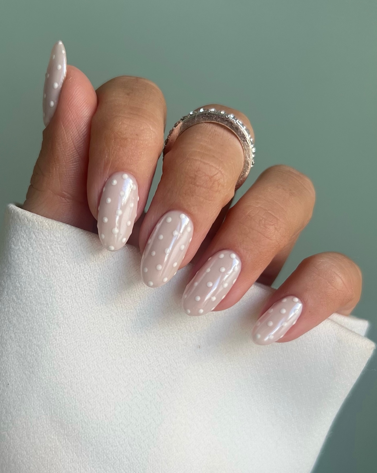 Glossy Nude Almond Nails With White Polka Dots