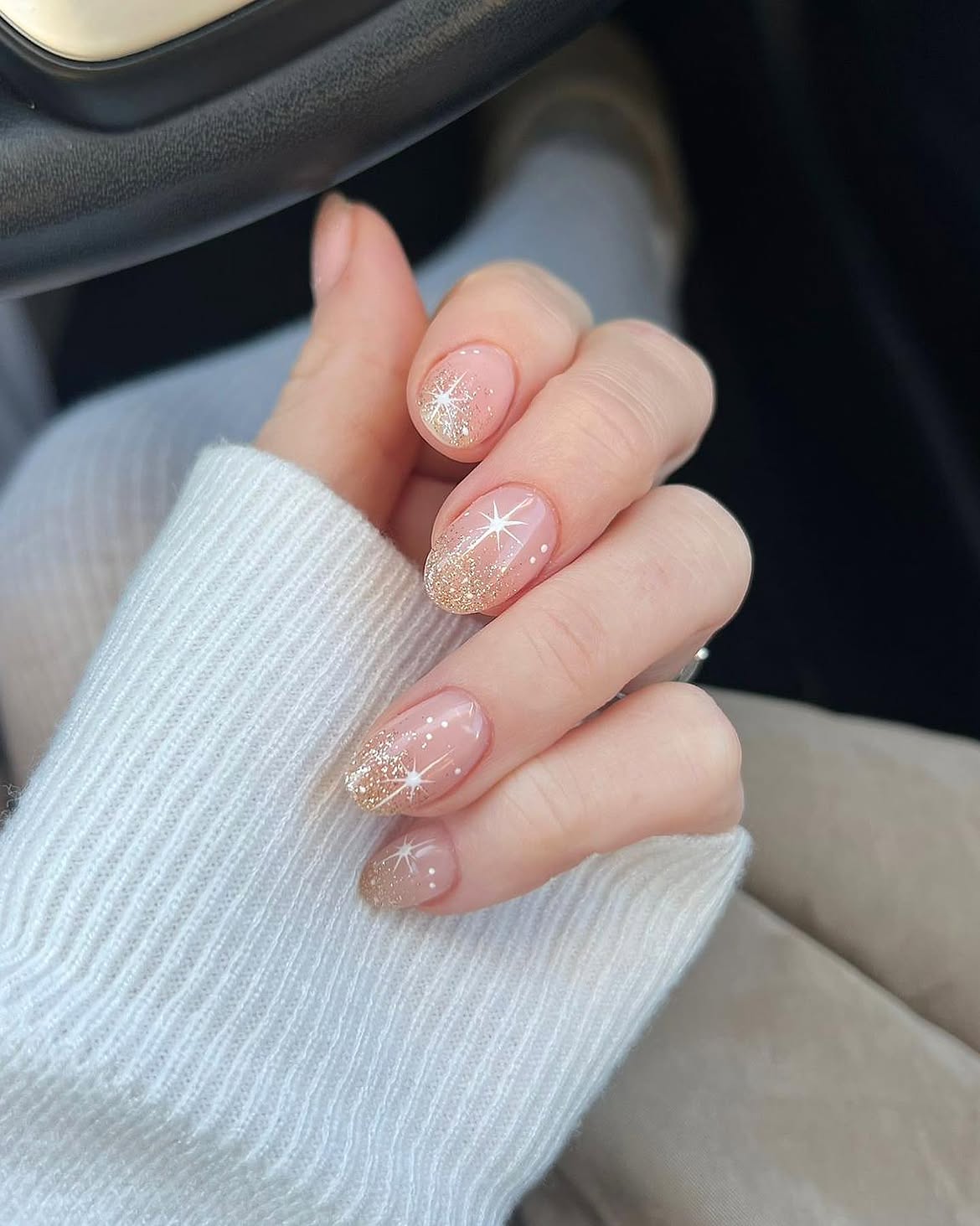 Glossy Nude Nails with Gold Glitter and White Starbursts