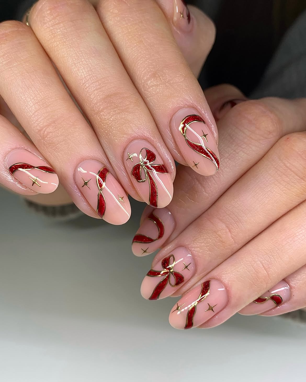 Glossy Nude Nails with Red Glitter Bows