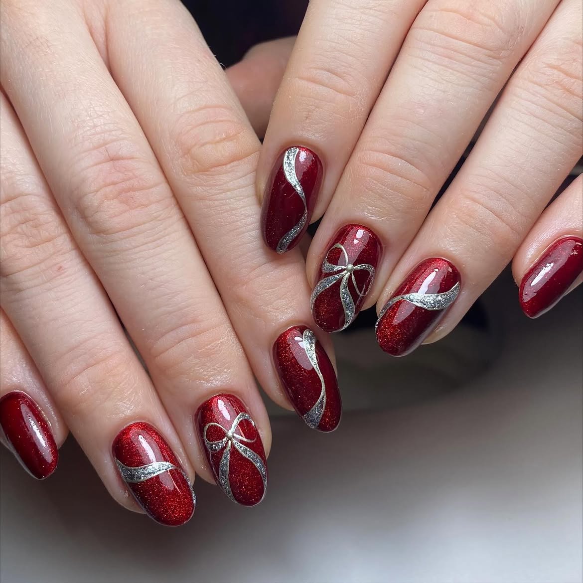 Glossy Red Shimmer Oval Nails With Silver Bows