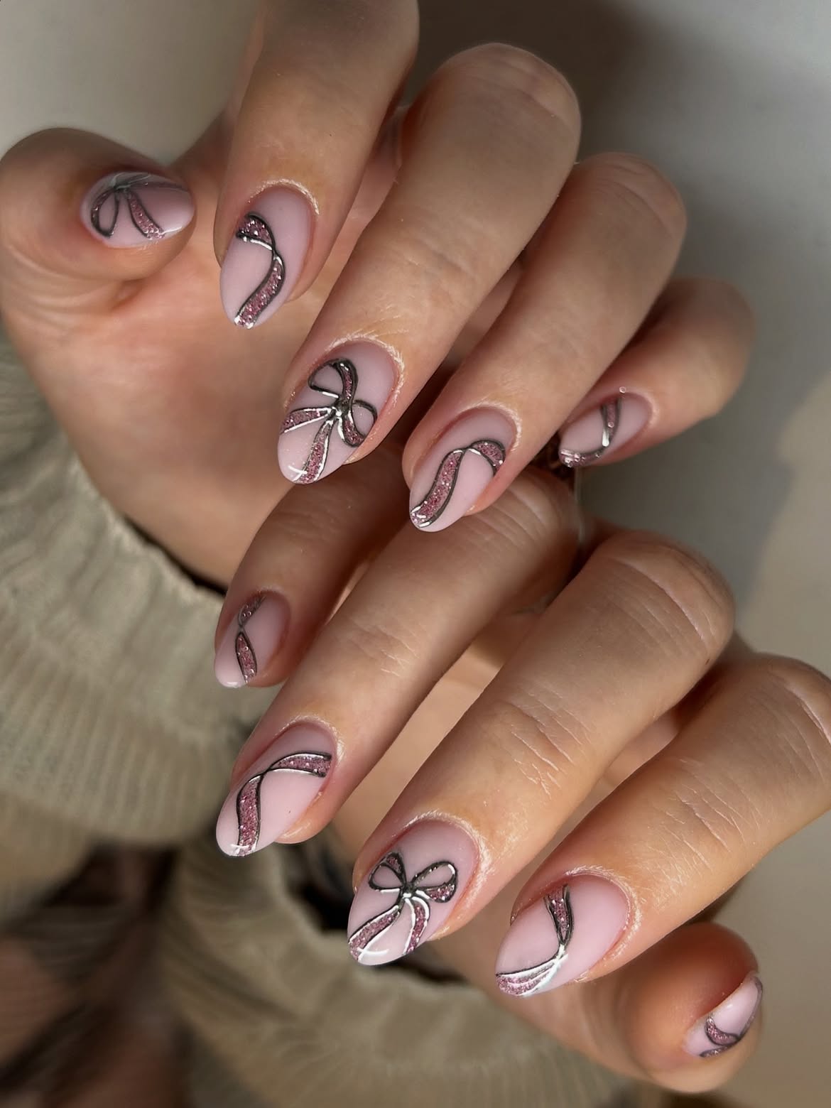 Matte Pink Almond Nails with Metallic Silver and Glitter Bow Art