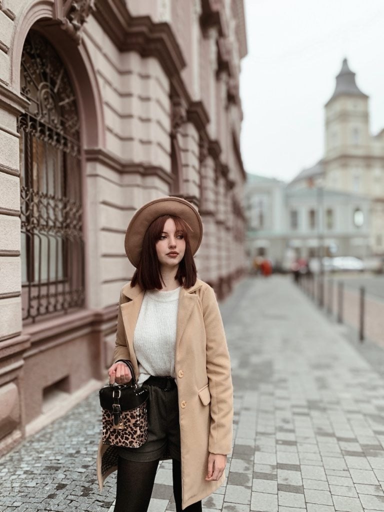 Beige coat over cream sweater and dark shorts Beige coat over cream sweater and dark shorts — Parisian Style