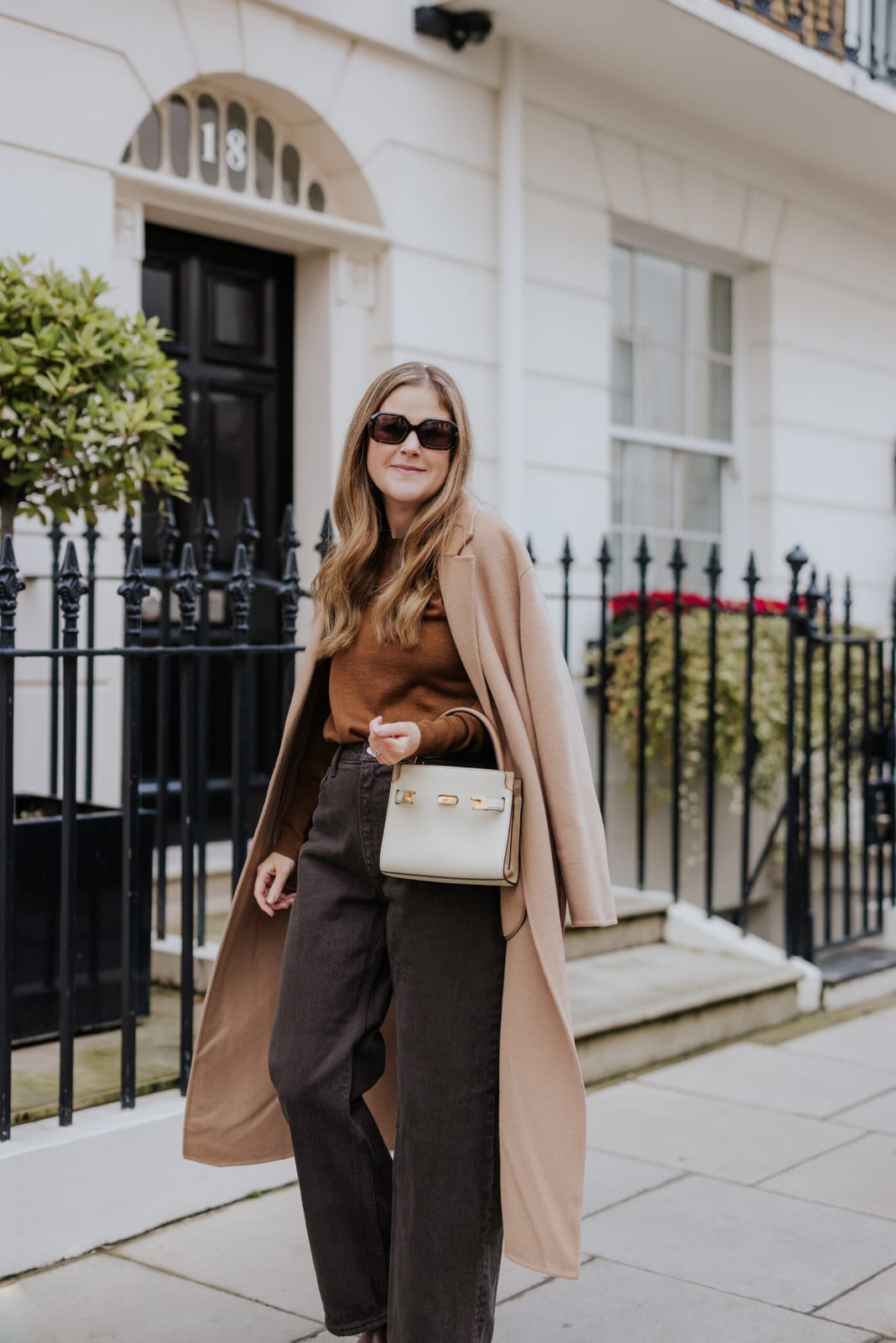 Long Tan Coat Over Brown Sweater And Dark Trousers Long Tan Coat Over Brown Sweater And Dark Trousers — Tan Outfits